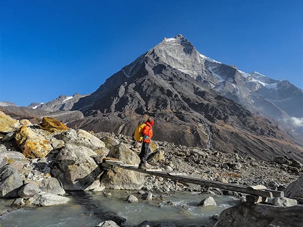 A man crossing a wooden bridge en-route to Khare on the Mera Peak climbing expedition
